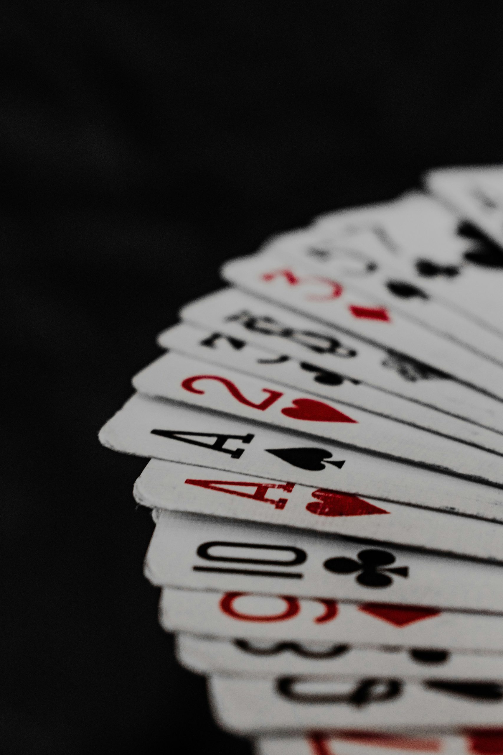 A set of playing cards splayed out in a fan across a black tabletop.